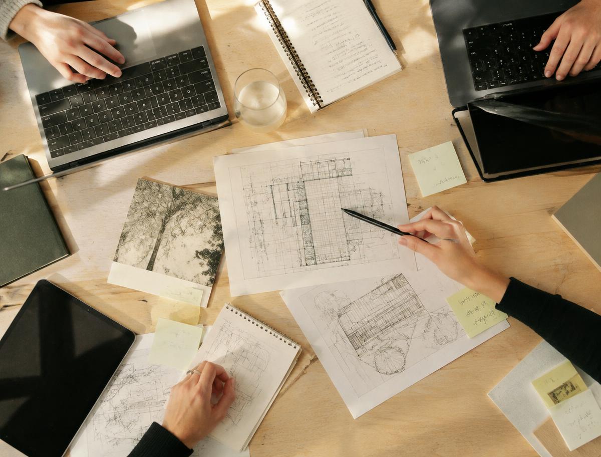 Overhead view of a shared table with laptops, sketches and sticky notes
